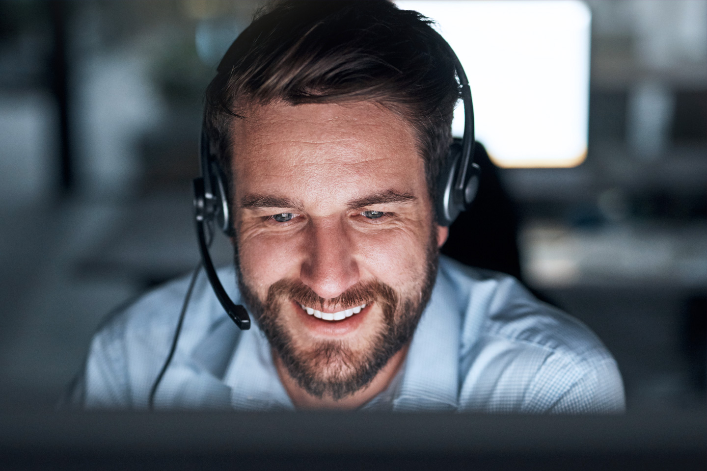 Man with headphone smiling looking at computer